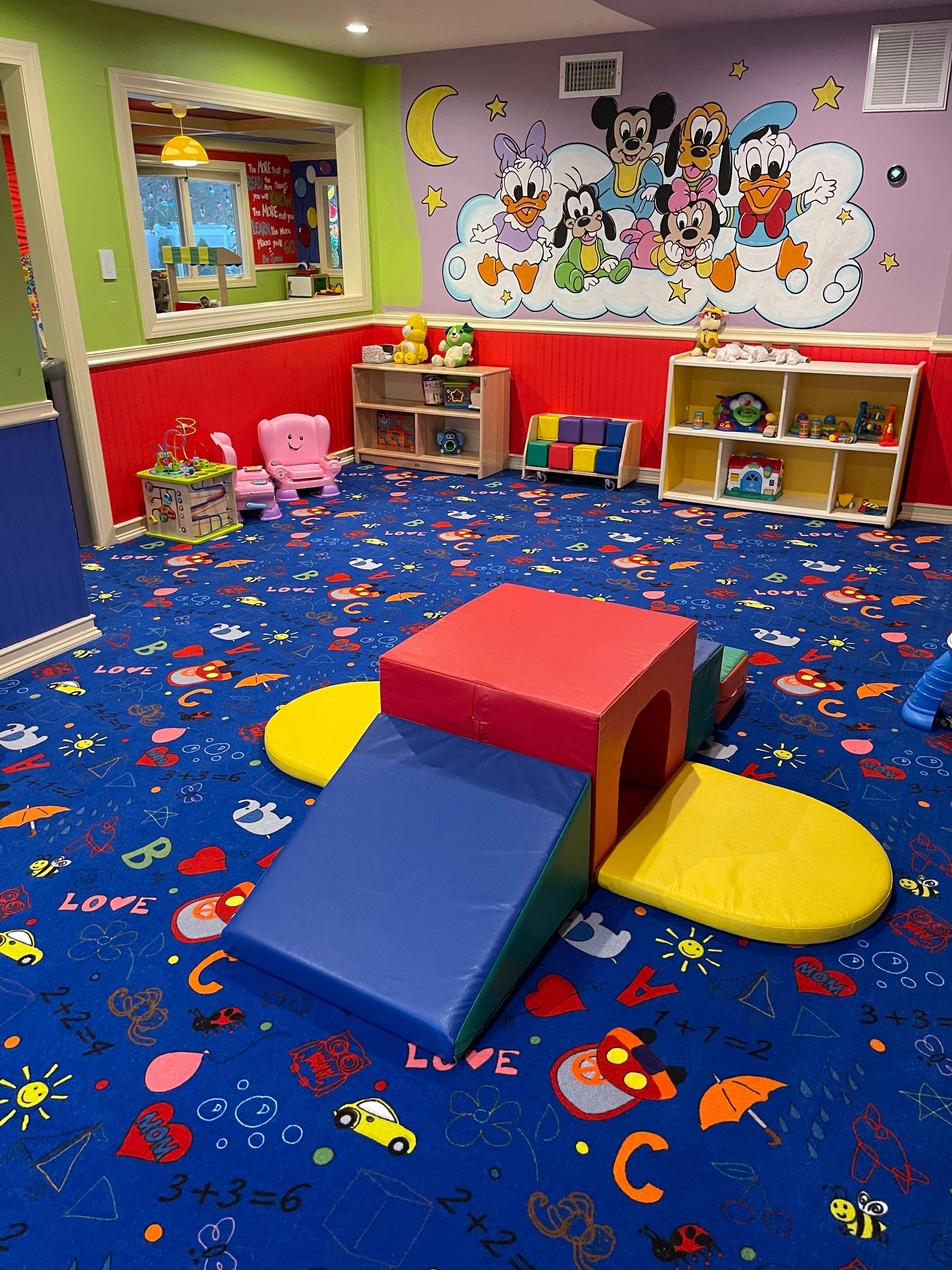 Colorful playroom with soft play climbing structure and Disney mural