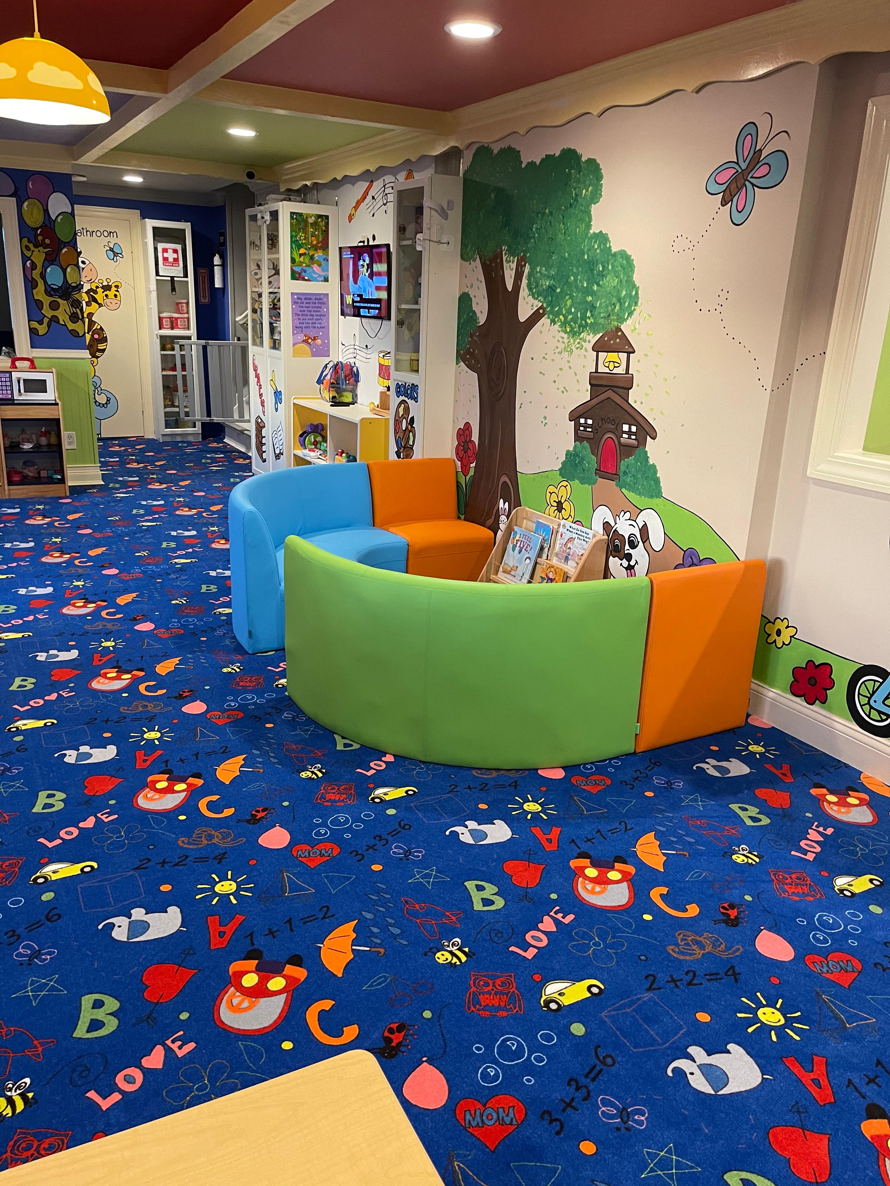 Reading nook with colorful soft seating and tree mural