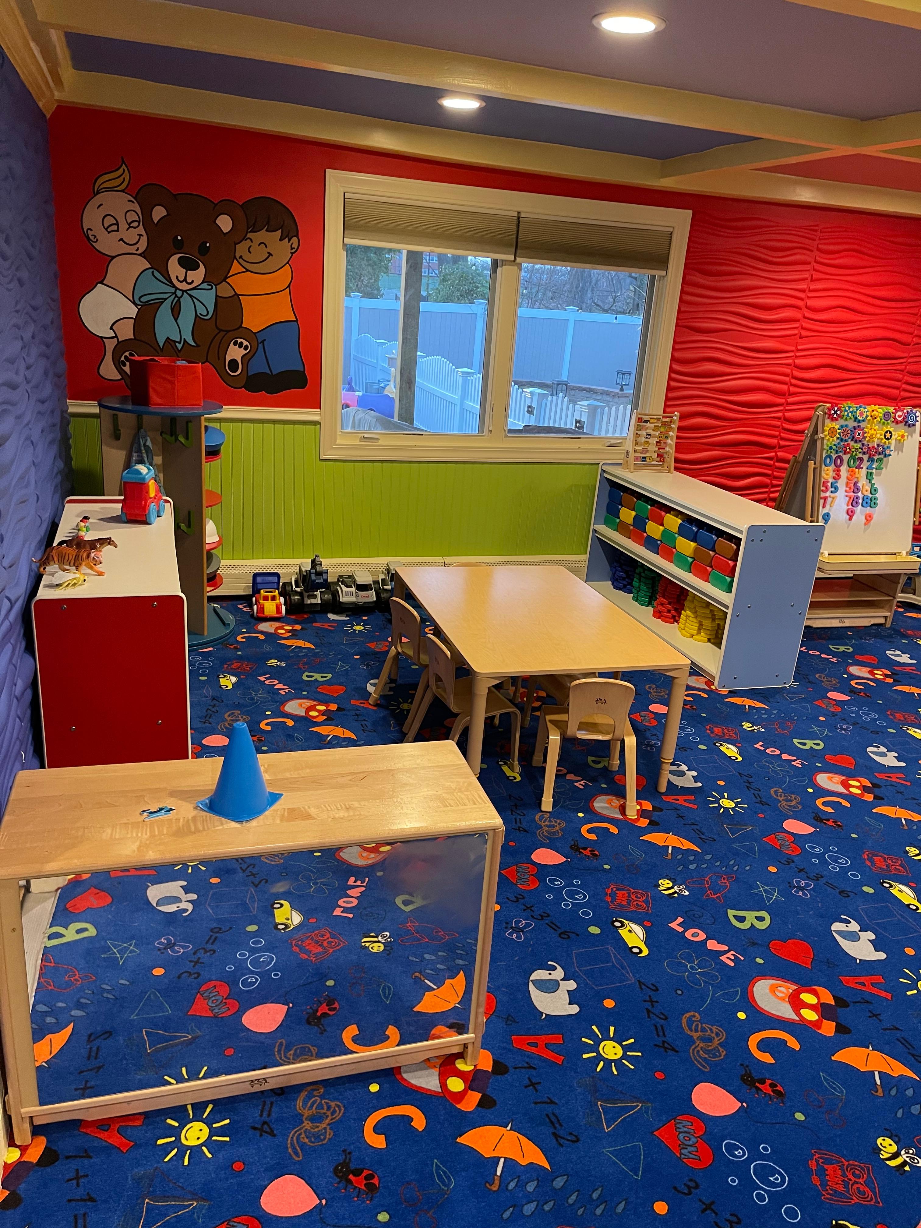 Toddler room with teddy bear mural and activity tables